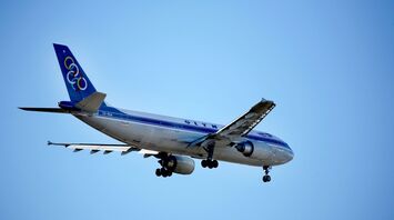 a blue and white Olympic Airways jet airliner flying in the sky
