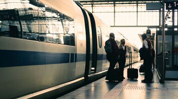Passengers boarding a modern high-speed train at a busy station