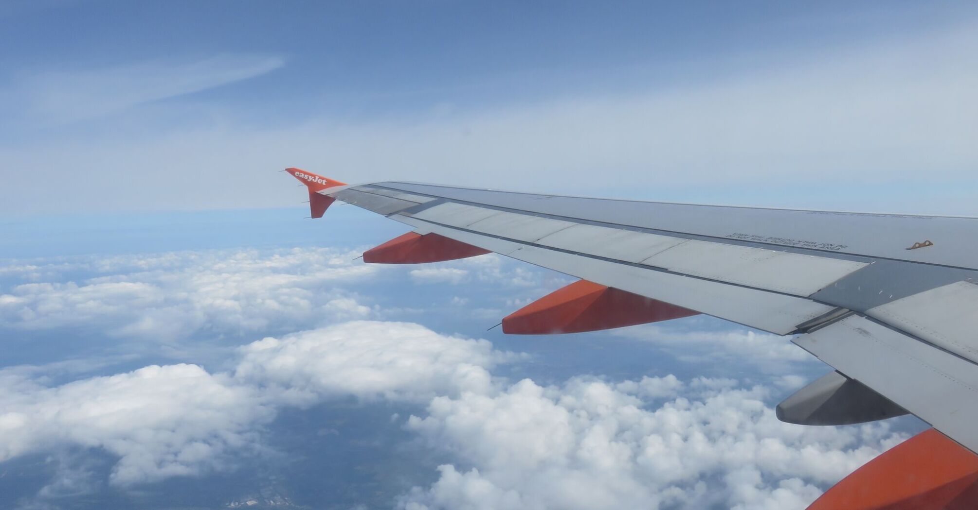 View from an EasyJet airplane window showing the wing and clouds