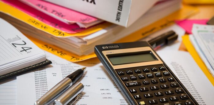 An array of income tax documents, calculator, and pens on a table