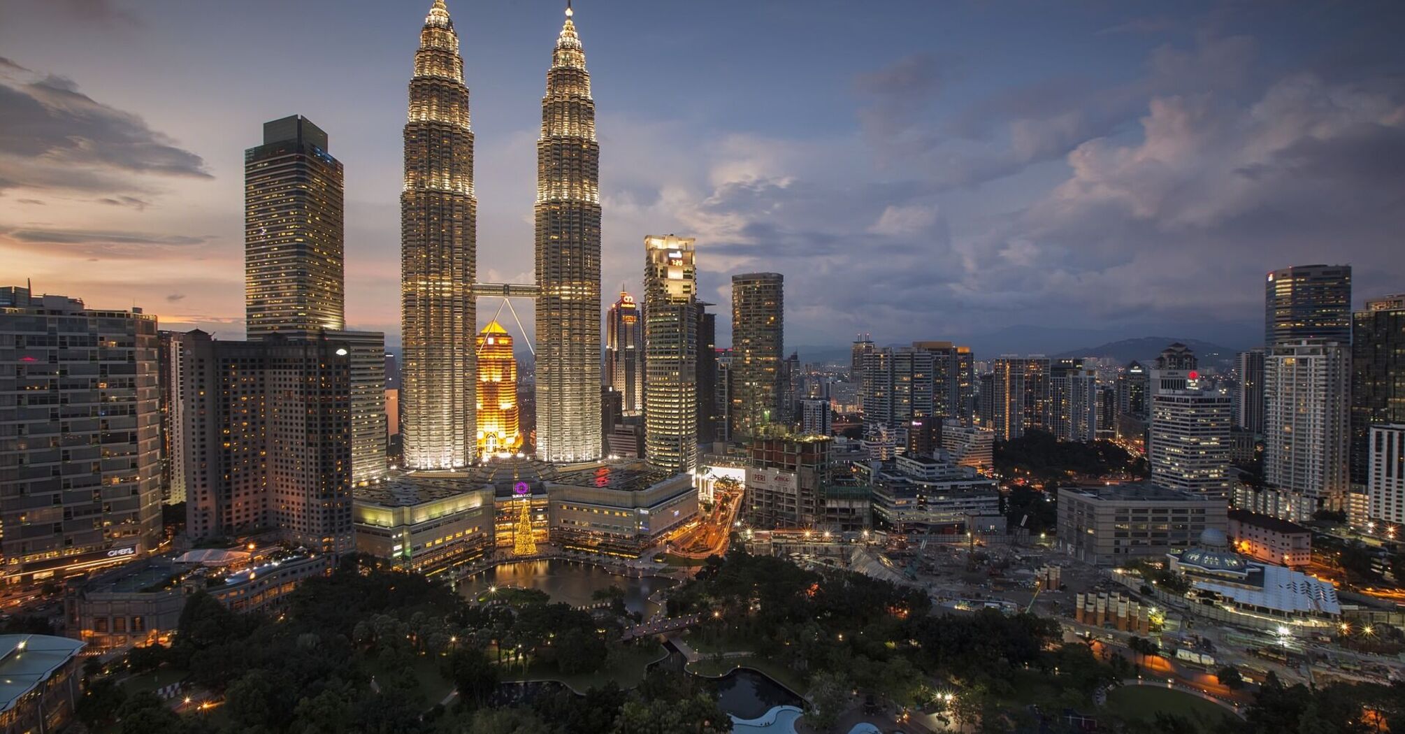 Aerial view of Kuala Lumpur skyline at dusk with the illuminated Petronas Twin Towers and surrounding city lights