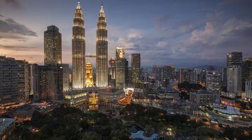 Aerial view of Kuala Lumpur skyline at dusk with the illuminated Petronas Twin Towers and surrounding city lights