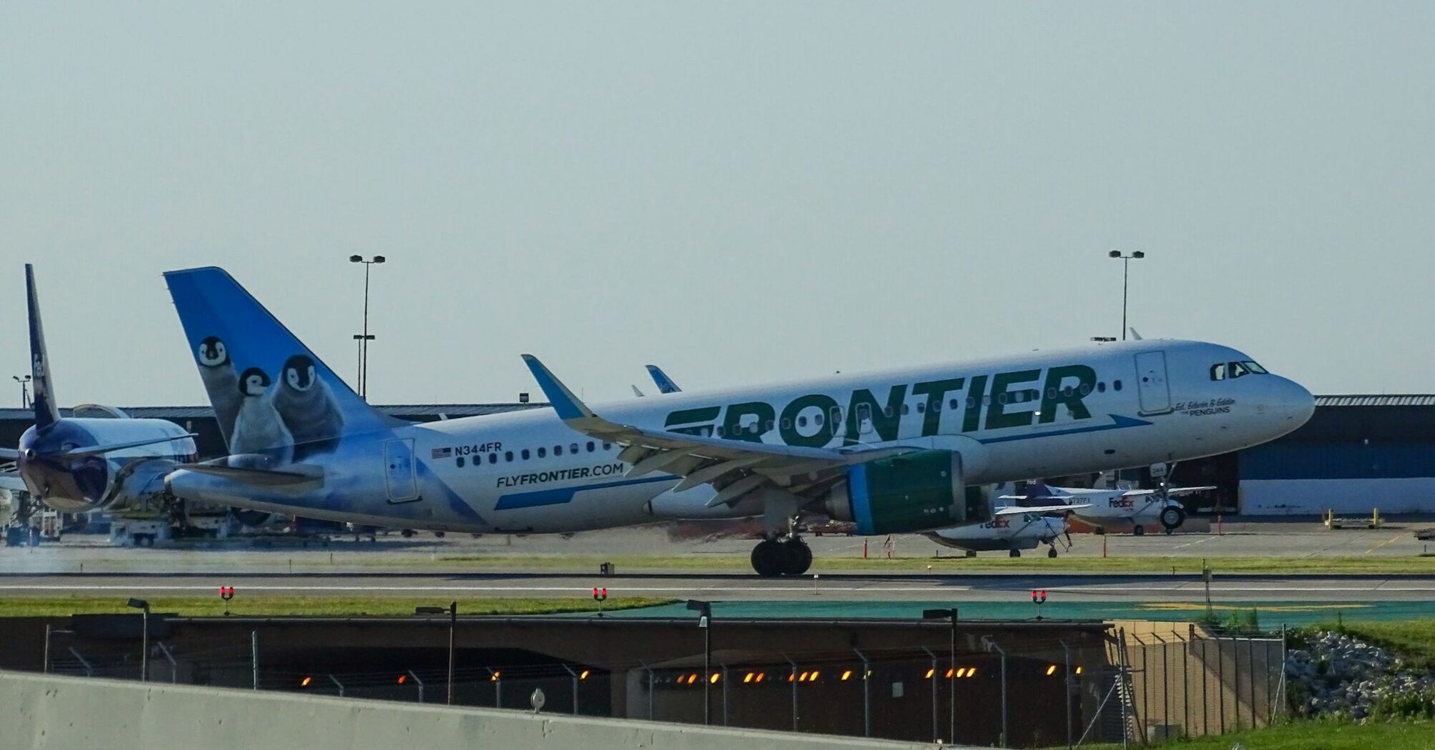 Frontier Airlines plane with penguin tail design on runway