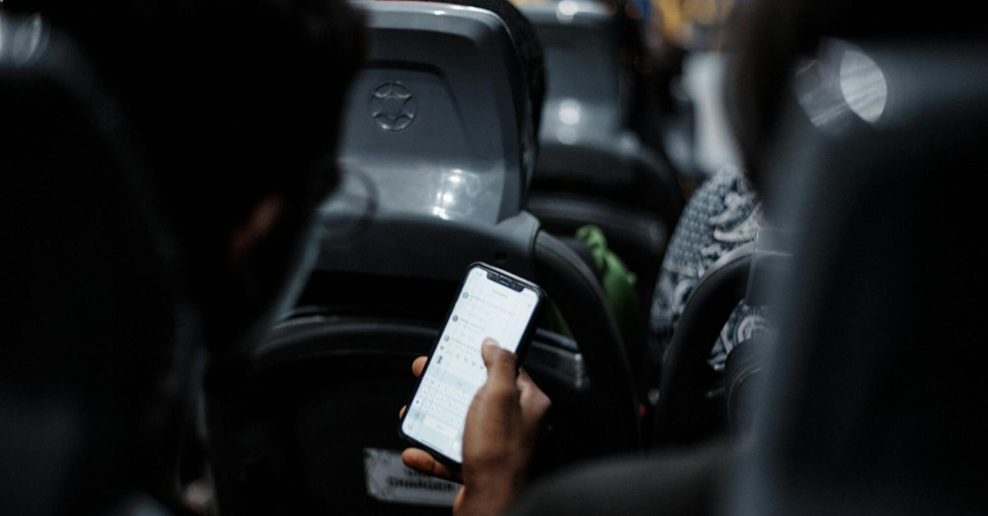 A person using a smartphone while traveling on a bus