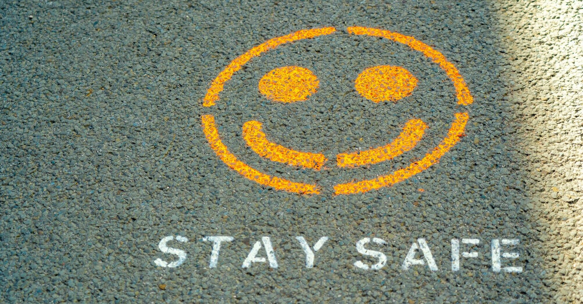 Yellow smiley face and 'Stay Safe' painted on pavement