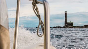 View of a lighthouse on Kimitoön Island from a boat, showcasing the rugged charm of the Finnish archipelago