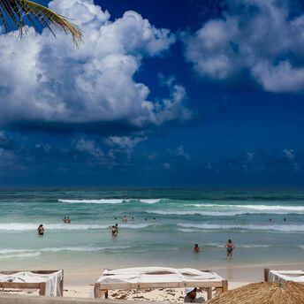 A sandy beach with people swimming in the ocean