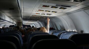 Child reaching up to overhead bins in airplane aisle