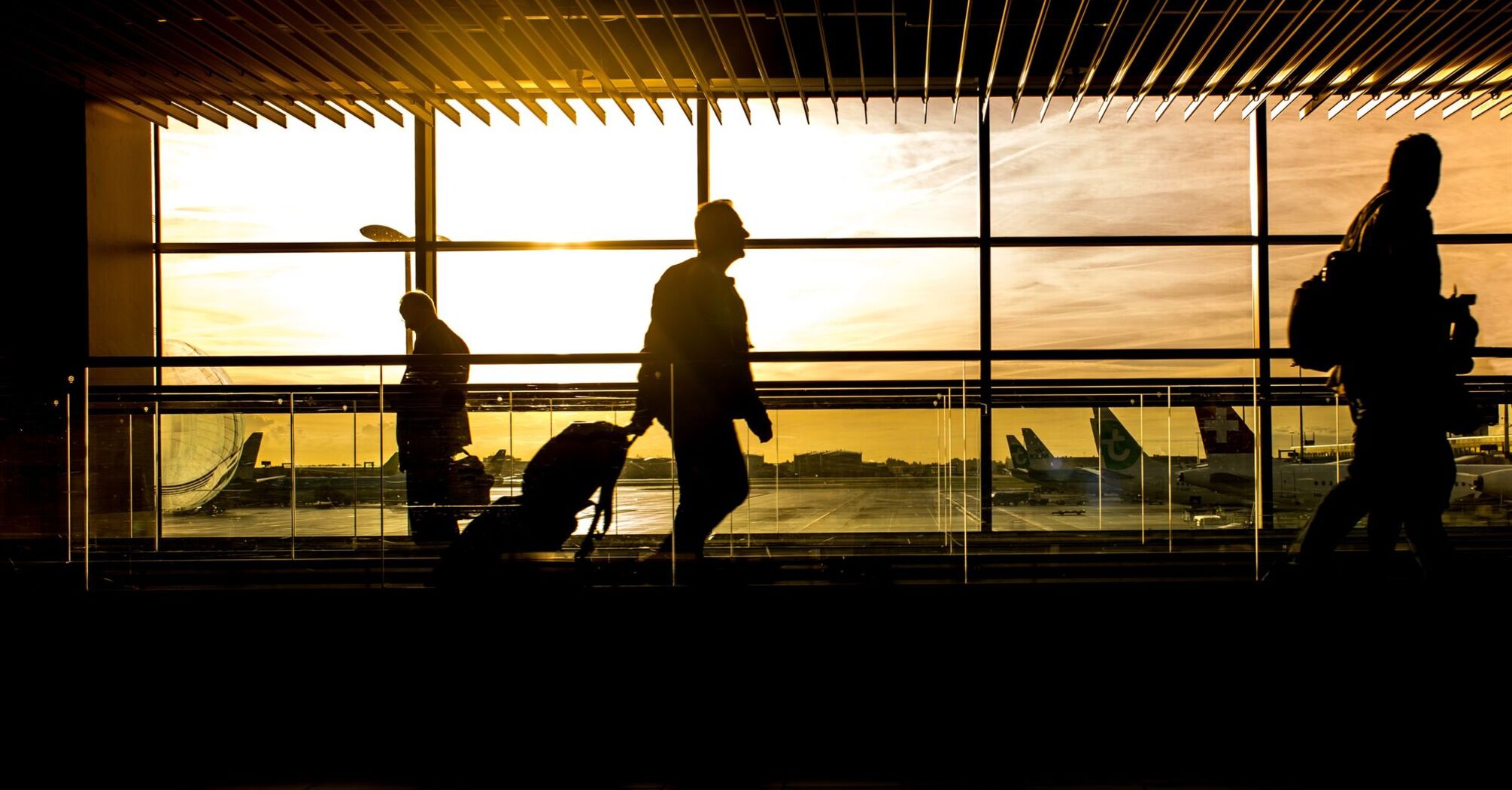 Silhouetted travelers at an airport terminal during sunset