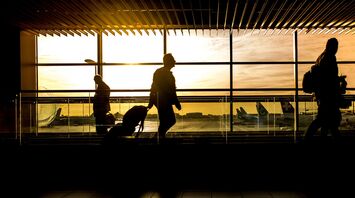 Silhouetted travelers at an airport terminal during sunset