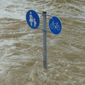 Traffic signs submerged in floodwater indicating pedestrian and bicycle paths