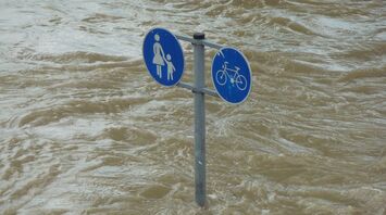 Traffic signs submerged in floodwater indicating pedestrian and bicycle paths