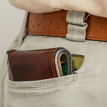 Wallet protruding from the back pocket of beige pants with a leather belt