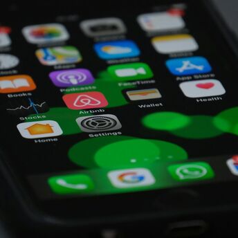 Close-up of a smartphone screen displaying various apps including Airbnb