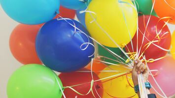 Hand holding colorful balloons with ribbons
