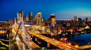 Twilight view of the Leonard P. Zakim Bunker Hill Memorial Bridge in Boston, with the city skyline lit up in the background
