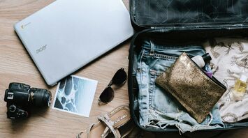 Open suitcase on a wooden floor packed with travel essentials