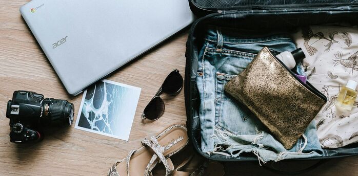 Open suitcase on a wooden floor packed with travel essentials