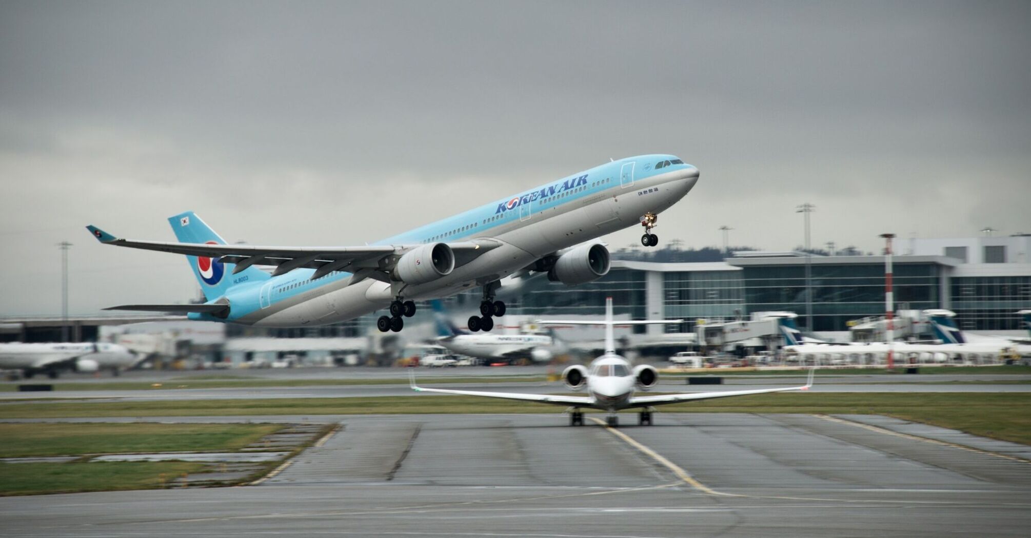 Korean Air plane taking off from an airport, cloudy background