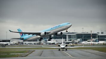 Korean Air plane taking off from an airport, cloudy background