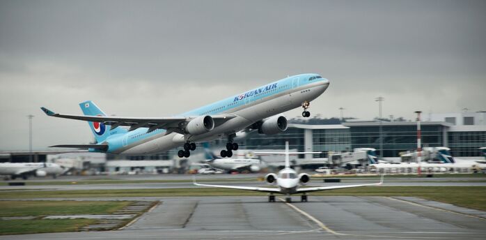 Korean Air plane taking off from an airport, cloudy background