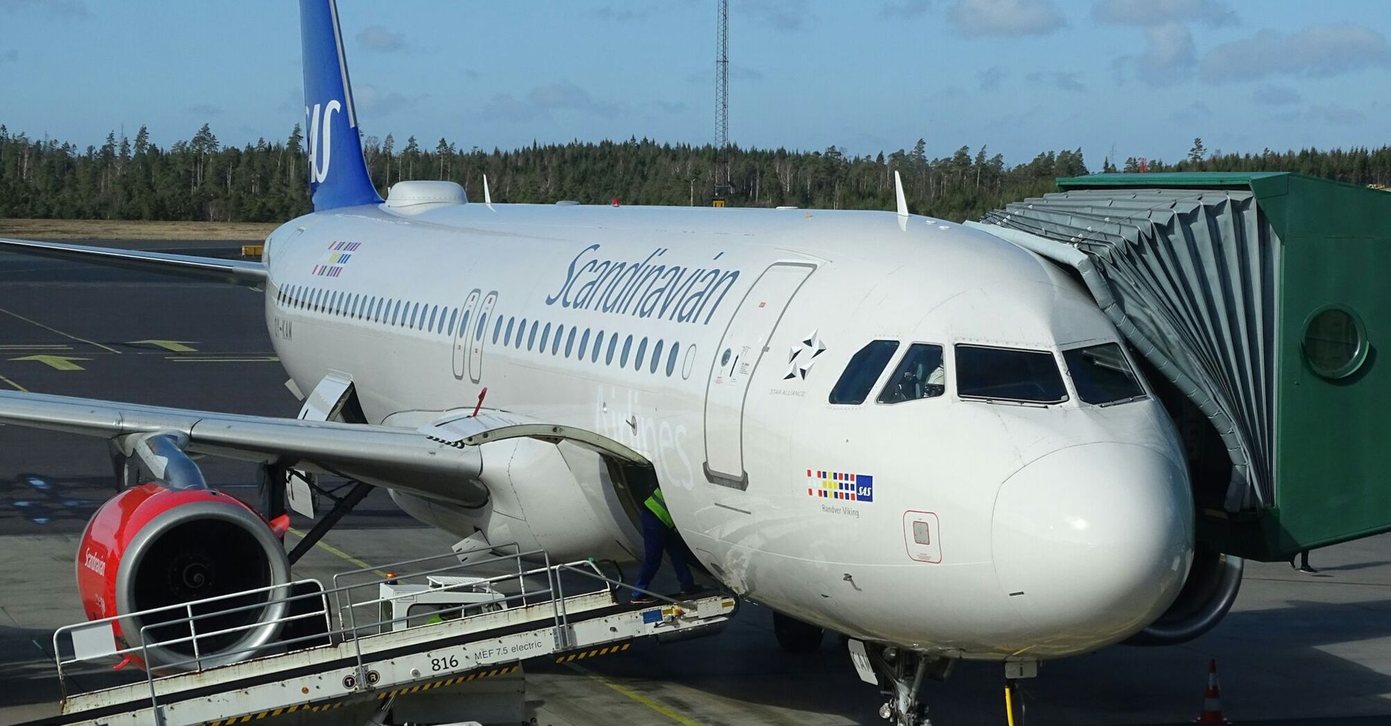 Scandinavian Airlines airplane docked at an airport terminal with jet bridge attached