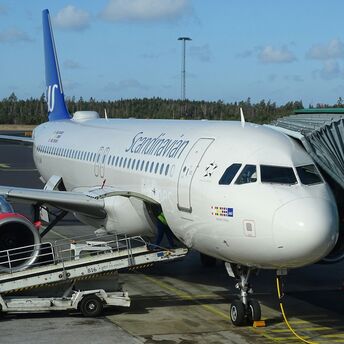 Scandinavian Airlines airplane docked at an airport terminal with jet bridge attached