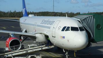 Scandinavian Airlines airplane docked at an airport terminal with jet bridge attached