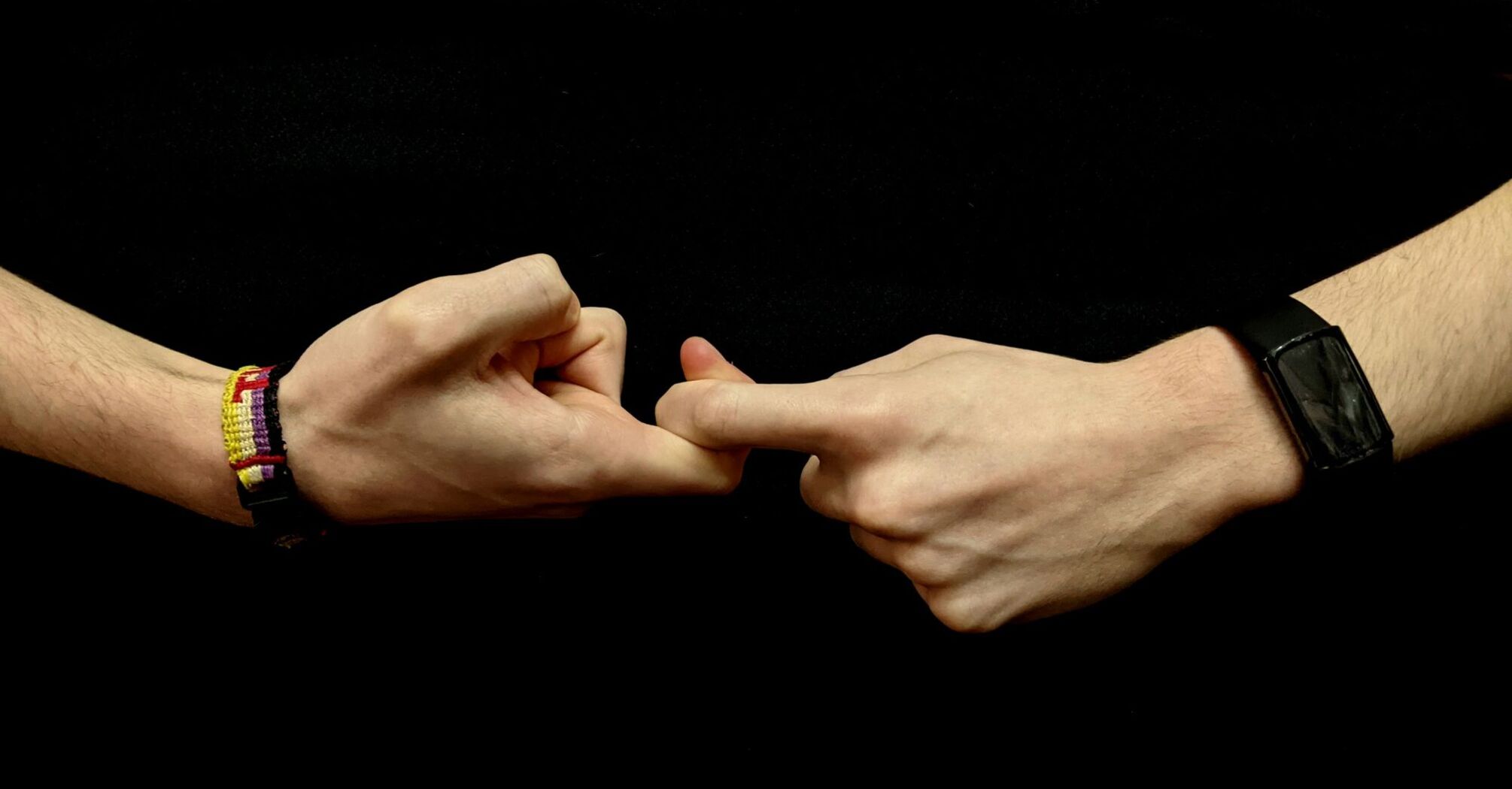 Two hands demonstrating a sign language gesture against a black background