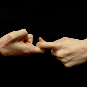 Two hands demonstrating a sign language gesture against a black background