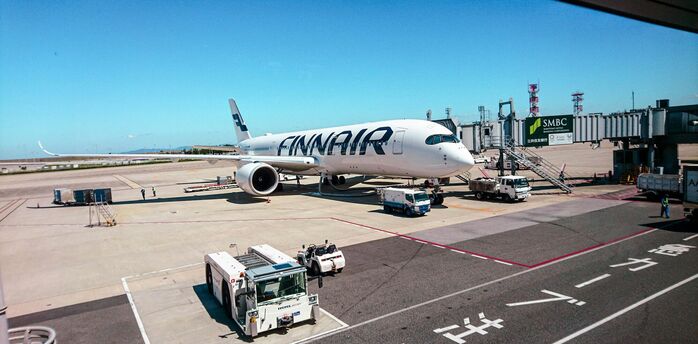 Finnair aircraft docked at an airport gate with ground support equipment and clear blue skies