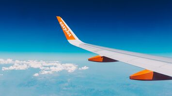View of a vibrant airplane wing against a backdrop of blue sky and fluffy white clouds