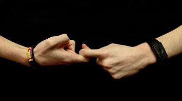 Two hands holding each other with bracelets on them