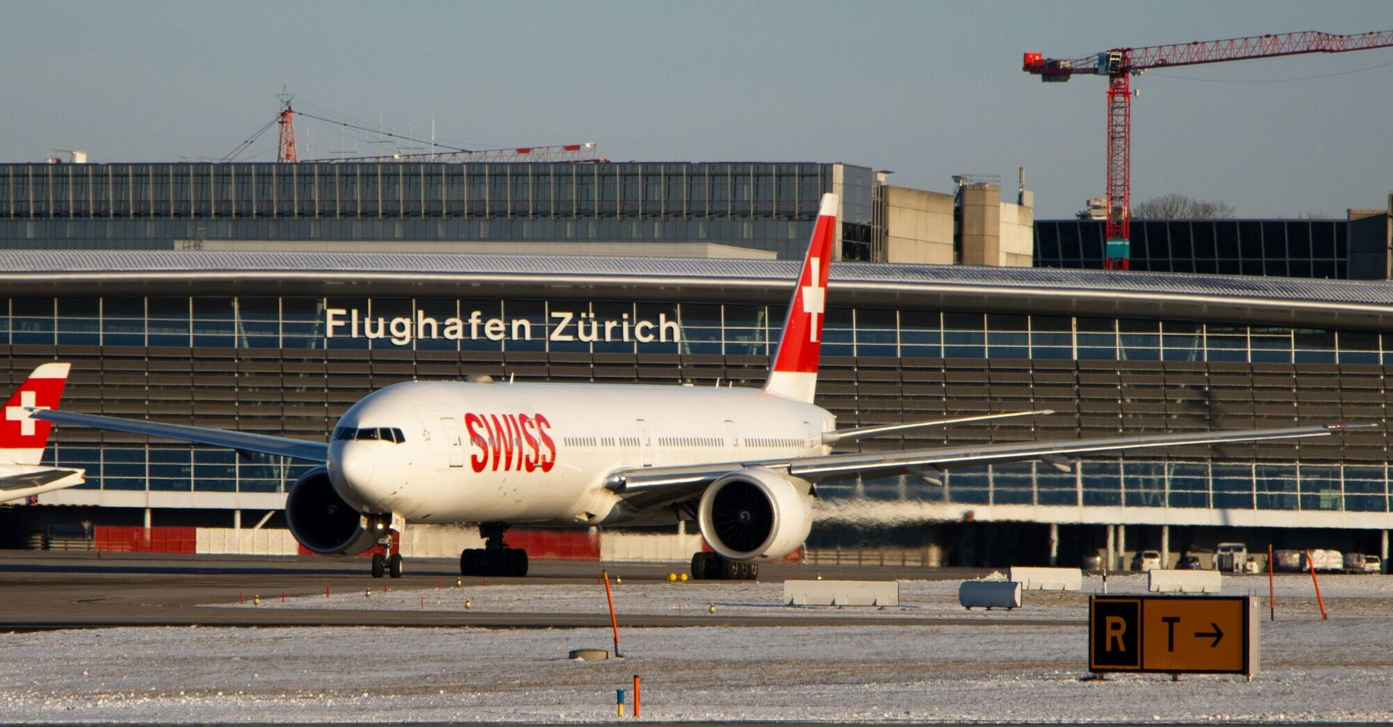 A SWISS airplane on a runway at Zurich Airport, with the airport terminal in the background