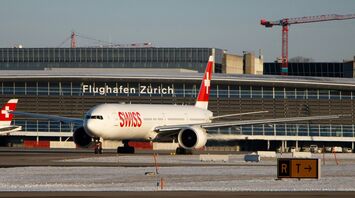 A SWISS airplane on a runway at Zurich Airport, with the airport terminal in the background