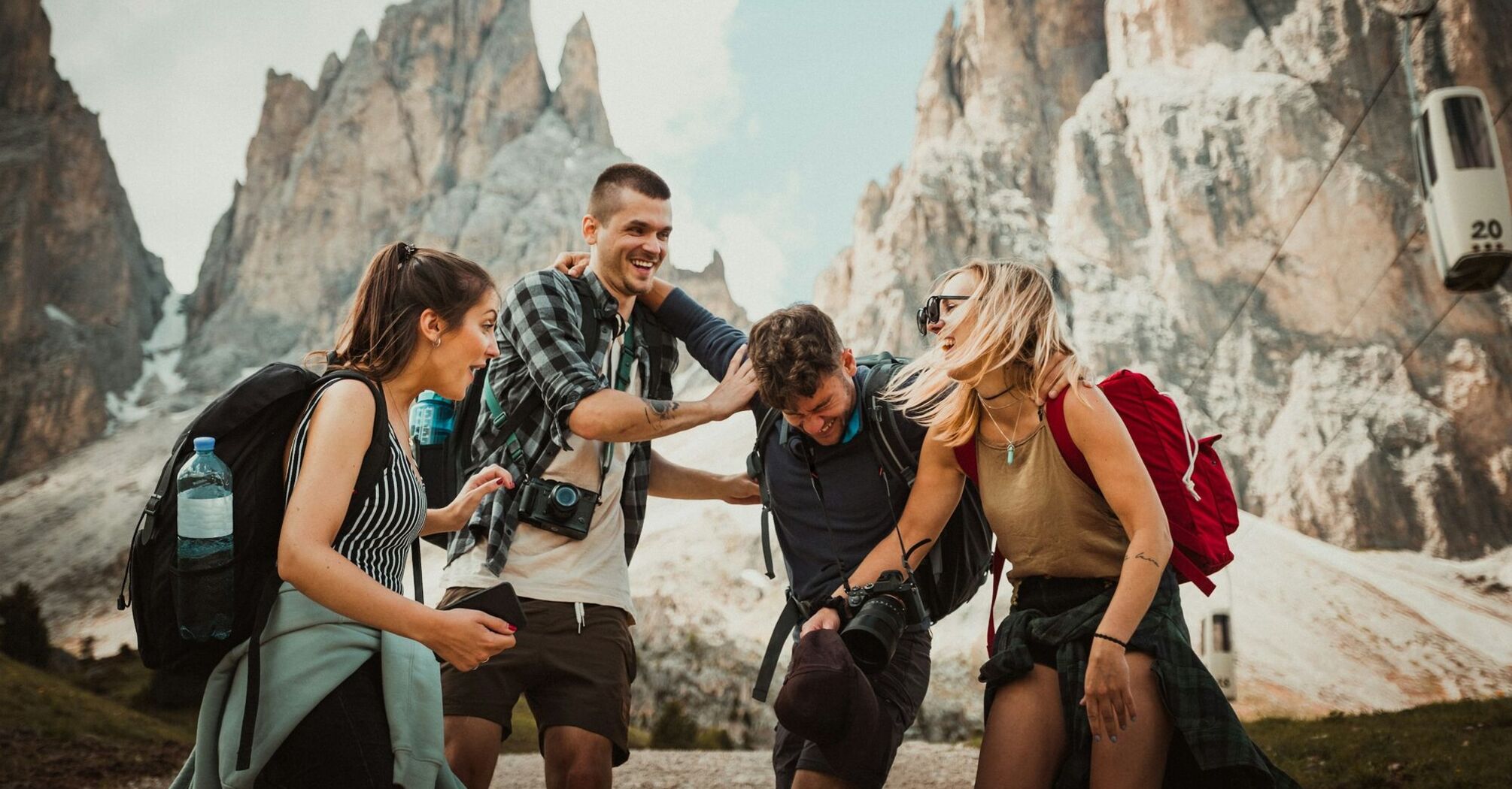 Group of friends laughing and hiking in the mountains, enjoying a sunny day outdoors