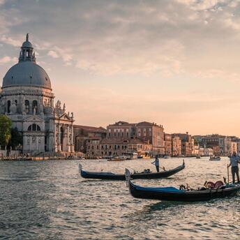 People ride gondolas on a canal in Venice