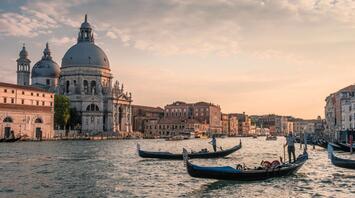 People ride gondolas on a canal in Venice