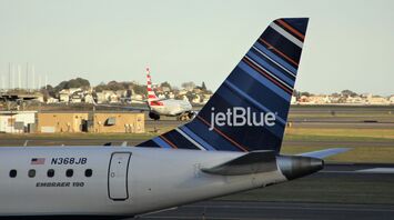 JetBlue Embraer 190 airplane tail with distinctive livery parked at an airport