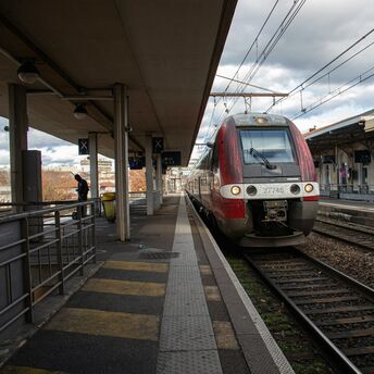 Train at a station with platforms and passengers on a cloudy day