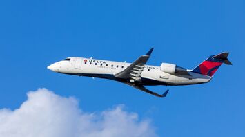 White blue and red delta airways airliner on flight under white and blue cloudy sky