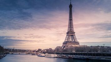 Eiffel Tower at sunrise with boats on the Seine River