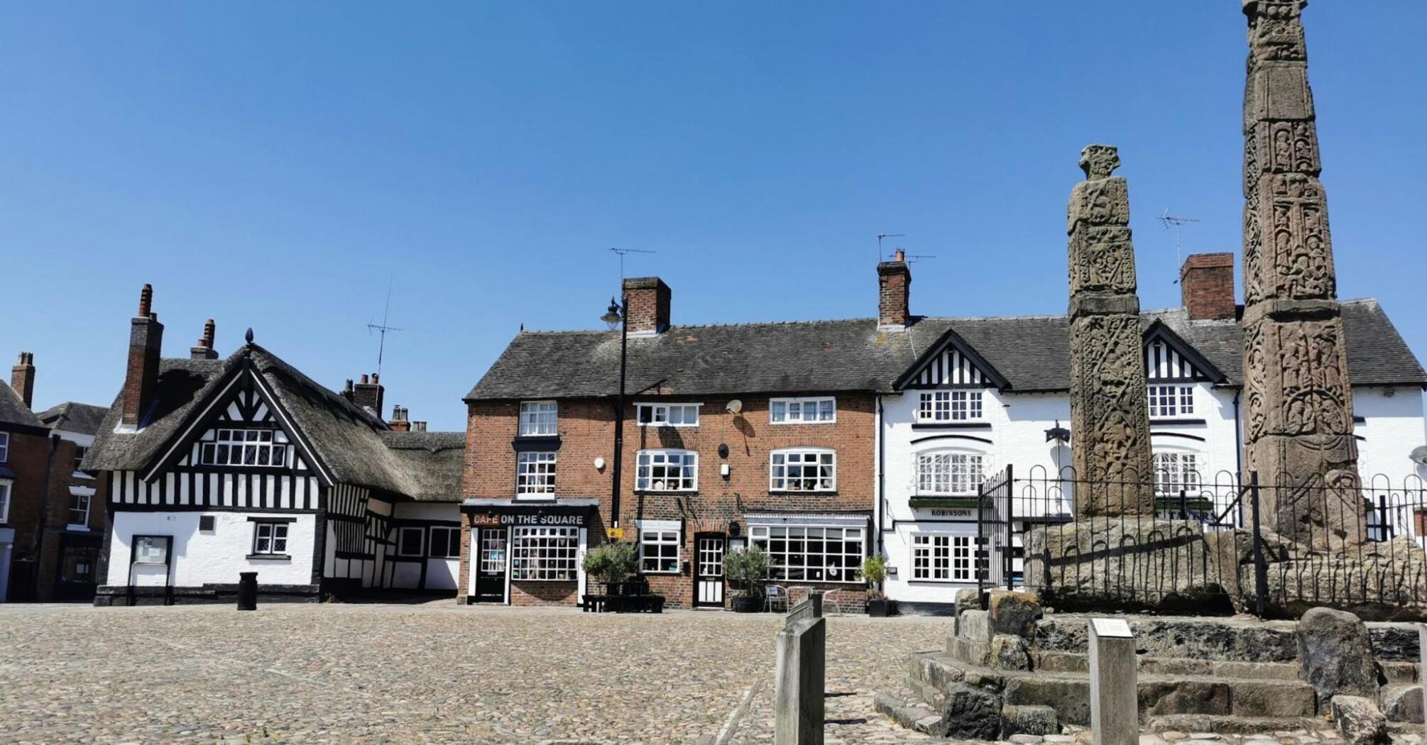 Historic town square in Cheshire East with old buildings and stone monuments