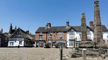 Historic town square in Cheshire East with old buildings and stone monuments