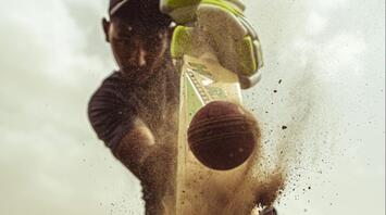 Close-up action shot of a cricket player hitting the ball with a bat
