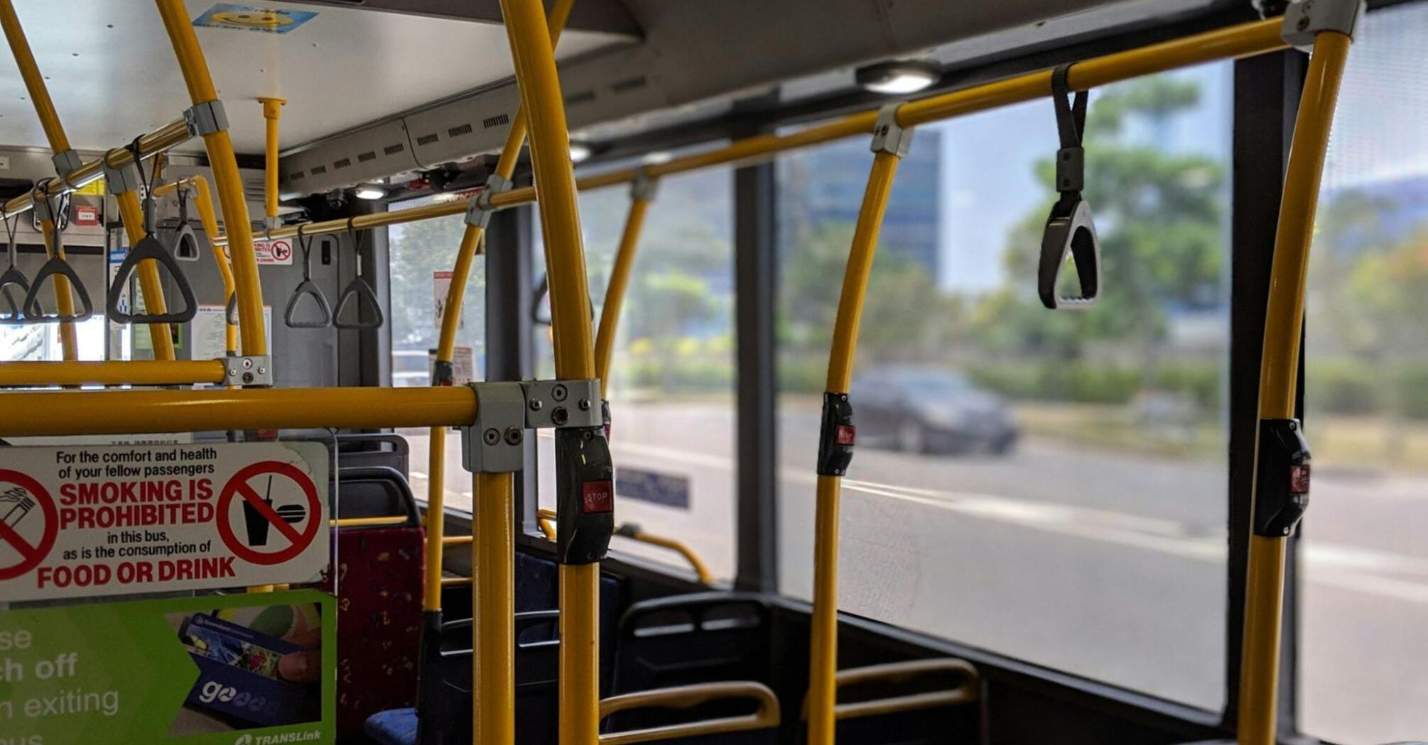 Interior of a Translink bus with yellow handrails and no smoking sign