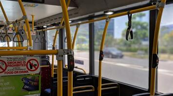 Interior of a Translink bus with yellow handrails and no smoking sign