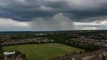 Aerial view of a town with dark storm clouds and rainfall in the distance