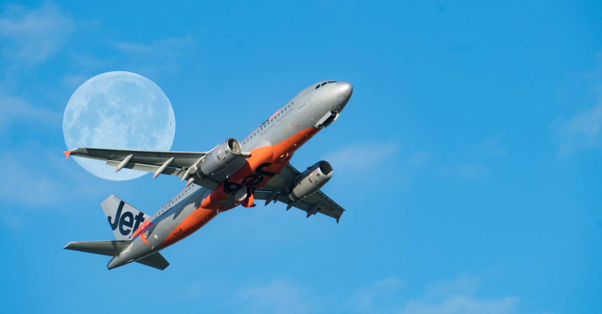 Jetstar Asia airplane in flight with the moon in the background