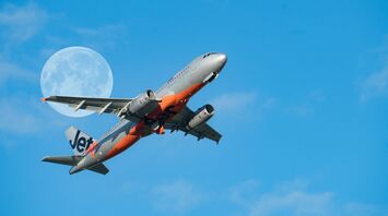 Jetstar Asia airplane in flight with the moon in the background